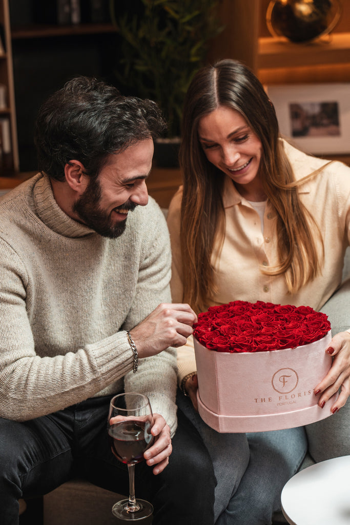 Casal a abrir caixa de veludo rosa com rosas vermelhas The Florist