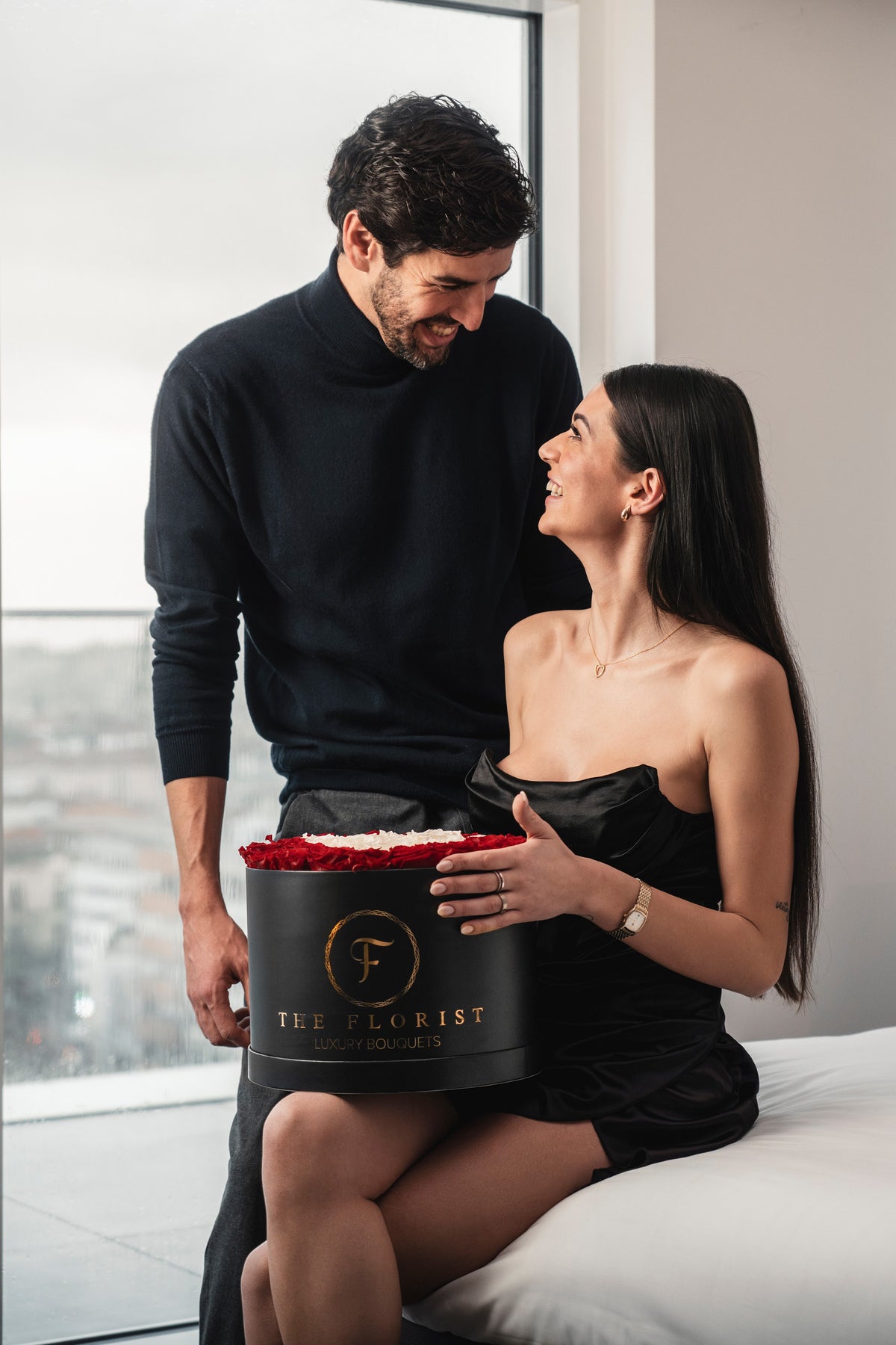 Casal elegante com caixa preta de rosas