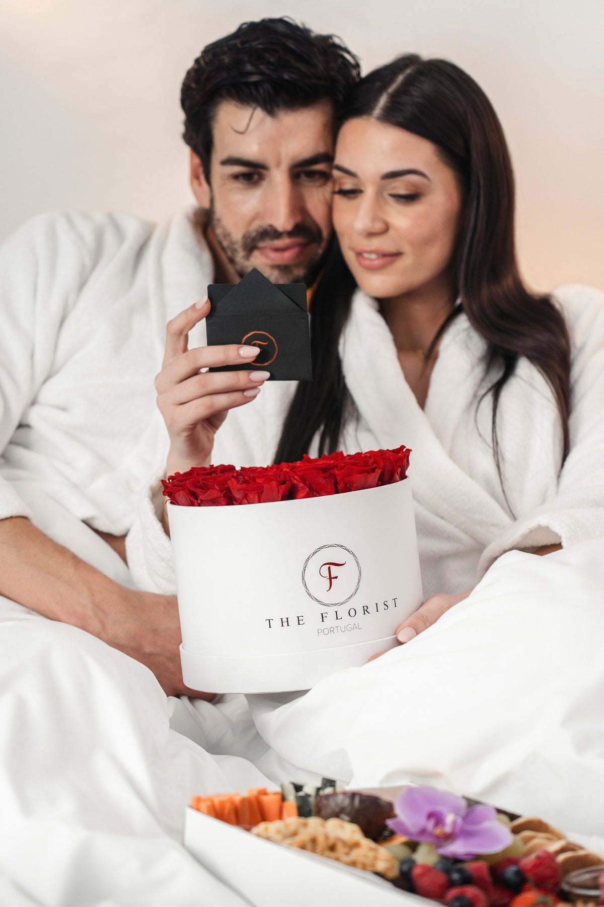 Casal com caixa branca de rosas vermelhas The Florist